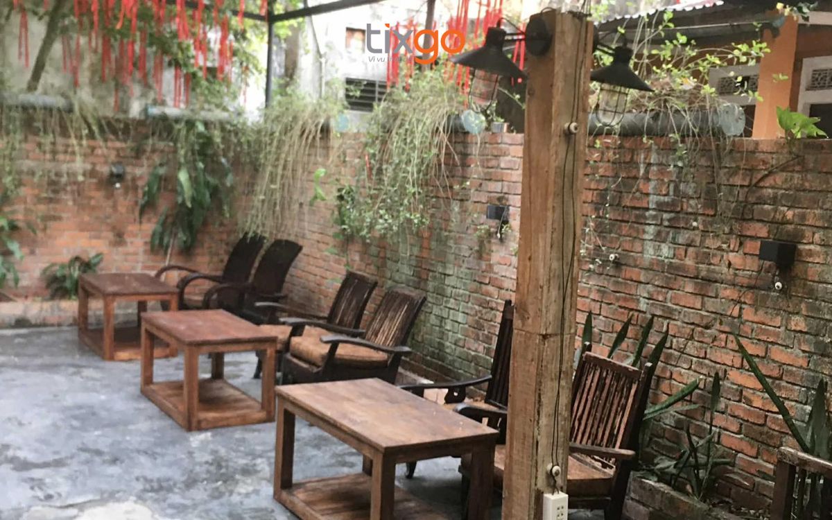 quán cafe đẹp ở huế Khoảng sân rêu phong với tường gạch thô và bàn ghế gỗ tạp mộc mạc.
