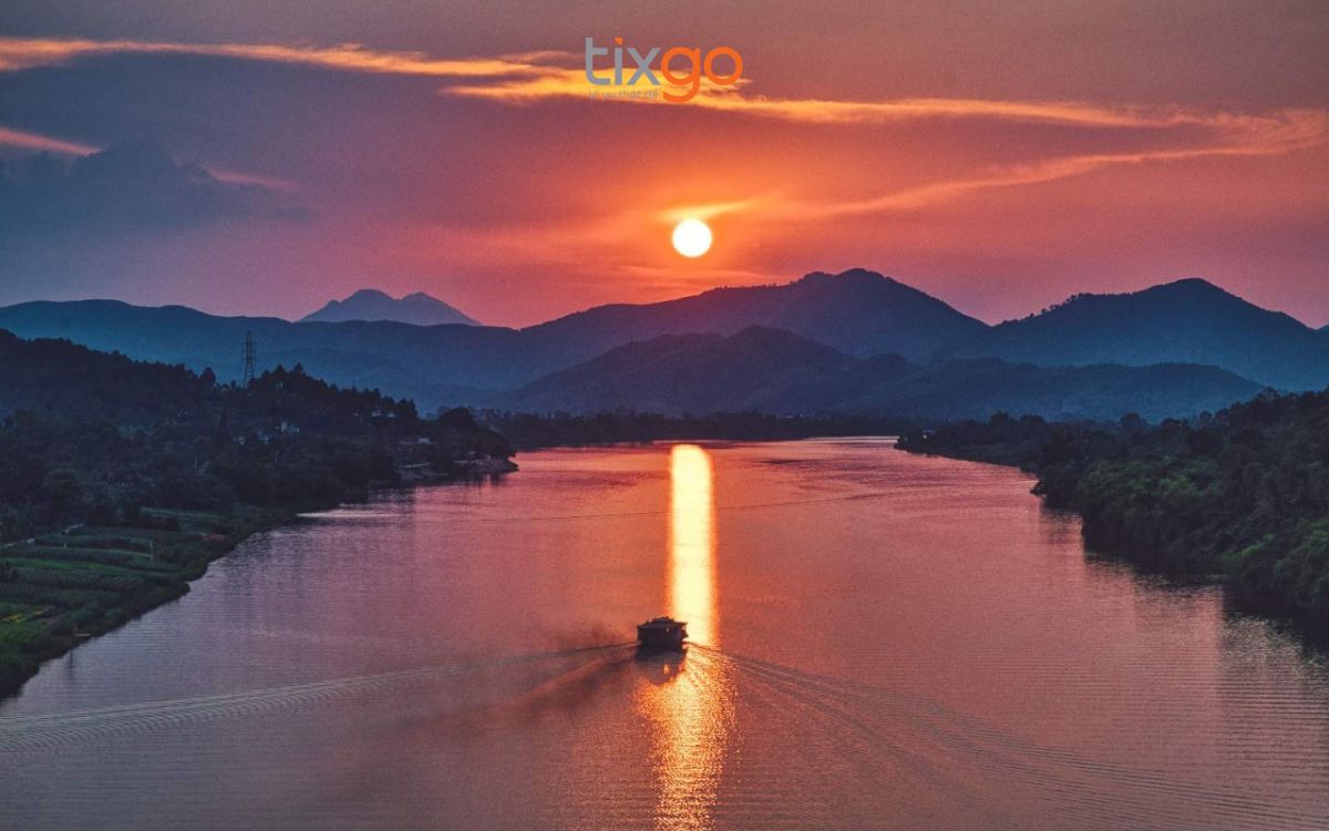 Khoảnh khắc hoàng hôn rực rỡ, mặt trời lặn dần xuống mặt sông tĩnh lặng.